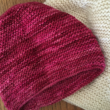 two hats next to each other, one of hand-dyed yarn and one of undyed yarn